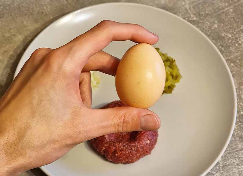 Many types of beef tartare are topped off with a fresh raw egg, however it's not mandatory to use it.