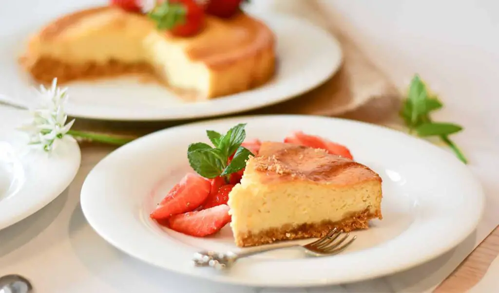 A small piece of delicious sernik served with strawberries.